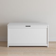 an empty white chest sitting on top of a hard wood floor