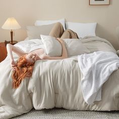 a woman laying on top of a bed in a bedroom next to a night stand