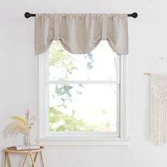 a white room with a window, chair and macrame hanging on the wall