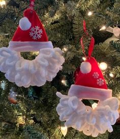 two christmas ornaments hanging from a tree with snowflakes and santa hats on them