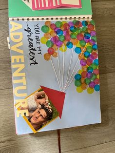 a book with a bunch of balloons attached to it's cover on a wooden table