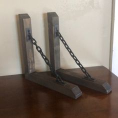 two pieces of metal chained to each other on top of a wooden table in front of a white wall