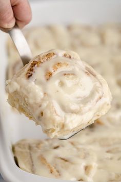 a spoonful of cinnamon rolls with cream cheese frosting in a casserole dish