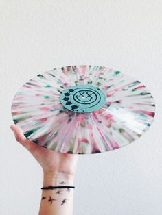 a person's hand holding up a colorful paper plate