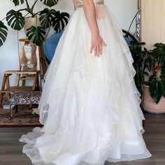 a woman in a white wedding dress standing next to a potted plant