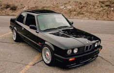 a black bmw is parked in a parking lot