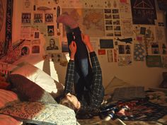 a person laying on top of a bed in a room with lots of papers and pictures