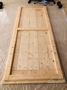 an unfinished bed frame is laying on top of the sheeted floor and ready to be built