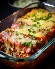 a casserole dish with meat, cheese and parsley in it on a table