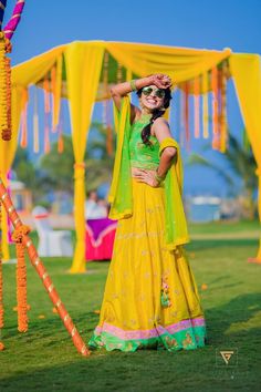 a woman in yellow and green outfit posing for the camera with her hands on her head