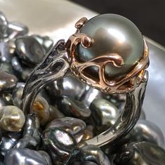 The un-drilled pearl protrudes inside and touches the skin of the wearer who feels instant ocean energy. The ring is fabricated in continuum silver and blackened by oxidation, the wave crown in 14k rose gold holds the Tahitian pearl intact. Pearl size: 12 mm Color options: grey, peacock or green - all natural color Luster: very good Grade: A, flawless Made in USA. Ocean Energy, Tahitian Pearls, The Wave, Pearl Size, Moana, Natural Color, All Natural, Turquoise Necklace, Color Options