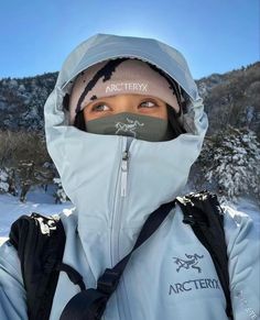 a woman wearing a white jacket and black backpack in the snow