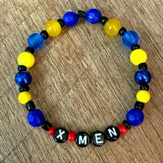 a beaded bracelet with the word x men written in black, yellow and blue beads