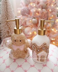 two soap dispensers sitting next to each other on a table in front of a christmas tree