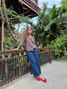 a woman leaning on a rail in front of some trees