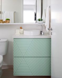 a white toilet sitting next to a green cabinet in a bathroom on top of a hard wood floor