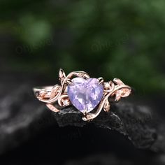 a heart shaped amethorate ring sitting on top of a black stone surface