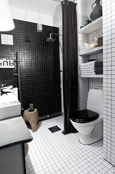 a bathroom with black and white tiles on the walls, floor, and shower curtain