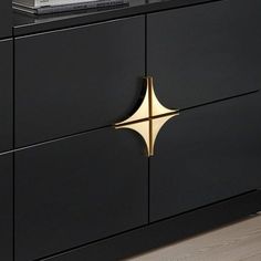 a black and gold sideboard with two drawers on each side that has a magazine on top