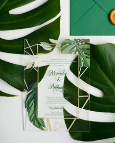 the wedding stationery is surrounded by tropical leaves