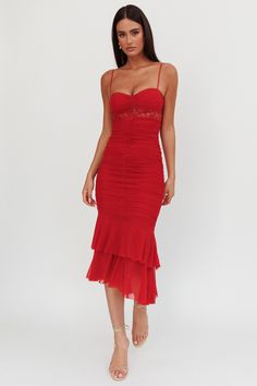 a woman wearing a red dress with spaghetti straps and ruffles on the bottom