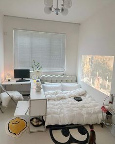 a white room with a bed, desk and computer on the floor next to a window