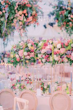 an arrangement of flowers and candles are on the tables at a wedding reception in pink, white and green colors