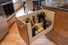 an open drawer in the middle of a kitchen with wine bottles and utensils