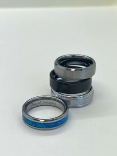 two silver rings with blue and black enamel inlays on the inside of them