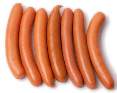 six hot dogs are lined up on a white surface