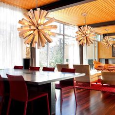 a dining room table with red chairs and a chandelier hanging from the ceiling