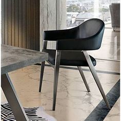 a black and white chair sitting next to a table in front of a large window