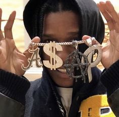 a young man holding up his glasses to show the dollar sign and letters on them