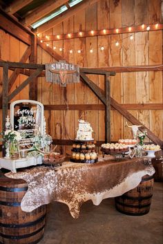 a table topped with cupcakes and cake next to a barrel filled with muffins