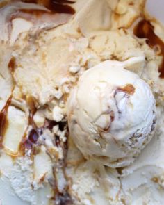 two scoops of ice cream with caramel and chocolate sauce in a white bowl