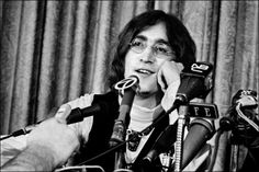 a man with glasses sitting in front of microphones