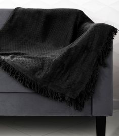 a gray couch with a black blanket on it