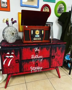 an old dresser with the rolling stones painted on it's side and various framed pictures