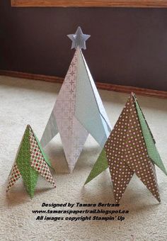 three origami christmas trees sitting on the floor