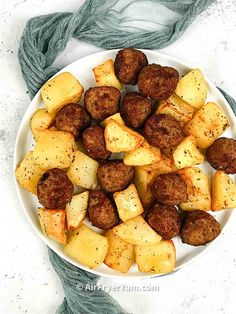 a white bowl filled with meatballs and potatoes on top of a blue yarn covered table