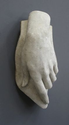 a white sculpture of a hand on a gray wall next to a black wall with a grey background