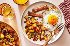 a plate with eggs, sausages and potatoes on it next to two glasses of orange juice