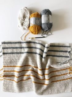 two balls of yarn sitting on top of a white table next to crochet hooks