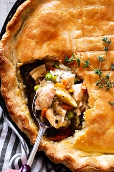 a chicken pot pie is shown with a spoon in it and garnished with fresh herbs