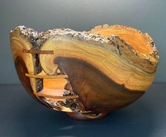 a wooden bowl sitting on top of a table next to a gray wall and floor