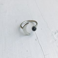 "Did you know that the darkened phase of the New Moon is said to provide strength? It allows us to contemplate and gather our best qualities so we may face what comes in the light. A striking ring in a crescent Moon shape with a set piece of black onyx. This celestial piece is petite enough to be a wardrobe staple yet bold enough to be a daily conversation piece. Available in your choice of silver tone or gold tone! Ring size: Adjustable (please do so carefully) Materials: Raw brass, onyx Moon s Crescent Ring, Crescent Moon Ring, Lunar Phase, Moon Shape, Moon Ring, Natural Stone Jewelry, Celestial Jewelry, Moon Shapes, New Moon