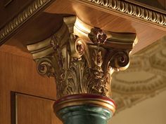 an ornate gold and green vase on top of a wooden shelf in front of a wall