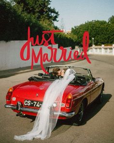 a bride and groom kissing in the back of a red convertible car with just married written on it