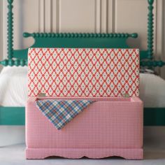 a bed with a pink and white checkered blanket next to a green headboard