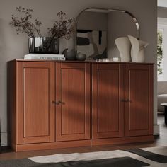 a large wooden cabinet sitting on top of a floor next to a mirror and vase